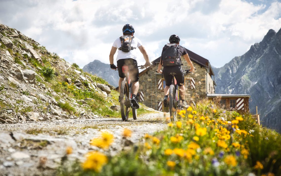 Mountainbiker erkunden blühende Alpenwiesen in Flirsch am Arlberg, ideale Aktivität im Sommer.