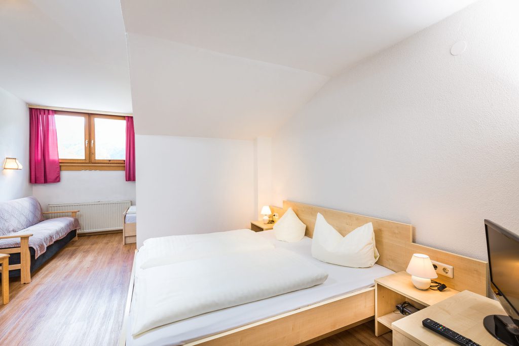 Bright double room in Hotel Grissemann Flirsch with sofa, wooden floors, and mountain view