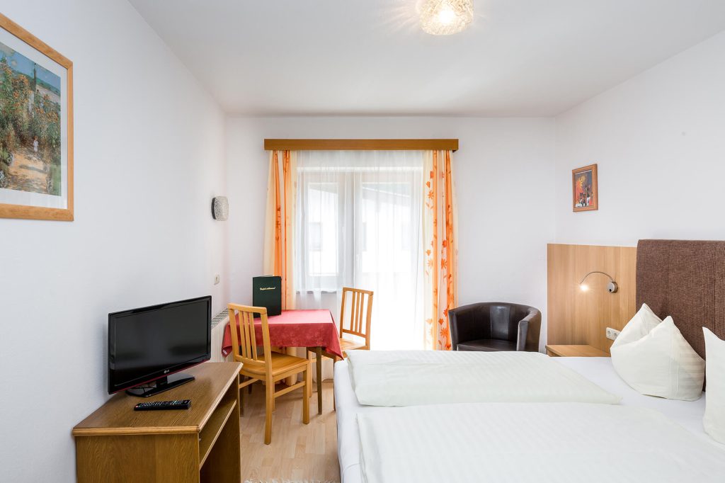 Bright room in Hotel Grissemann Flirsch, double bed, TV, seating area, balcony view of Arlberg