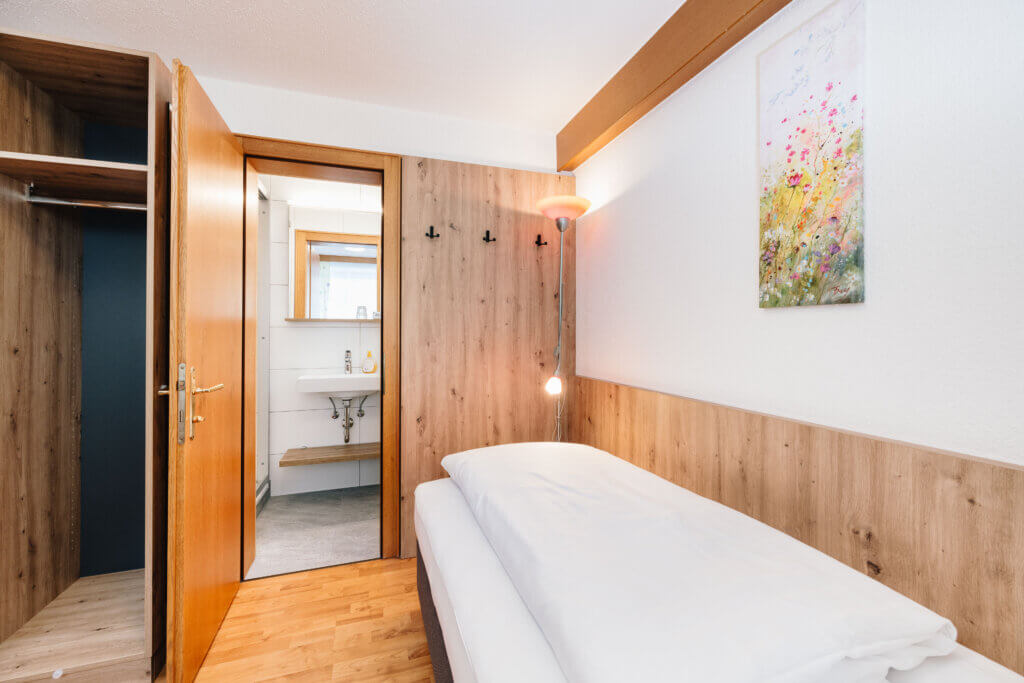Single room in Hotel Grissemann Flirsch am Arlberg with wood decor, bathroom, and wall picture